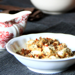 Una ciotolina con muesli di semi e frutta fresca e secca accompagnato da un bricco di latte di mandorla